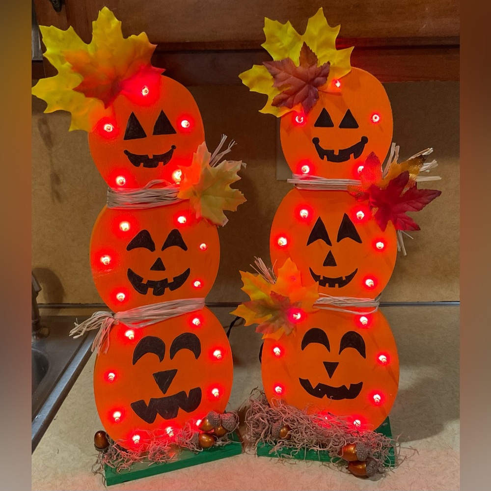 Handcrafted/ hand painted wood Halloween stacked pumpkins with orange lights on.